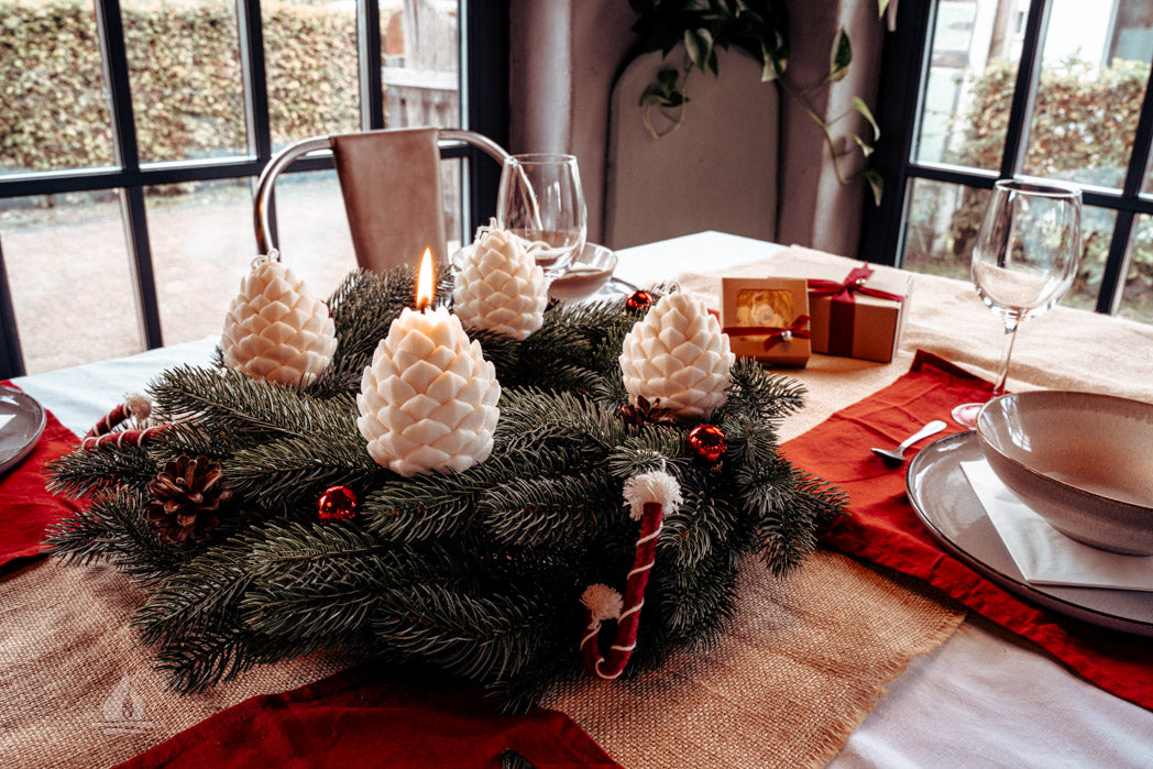Adventskranz auf weihnachtlichem Tisch mit Tannenzapfenkerzen