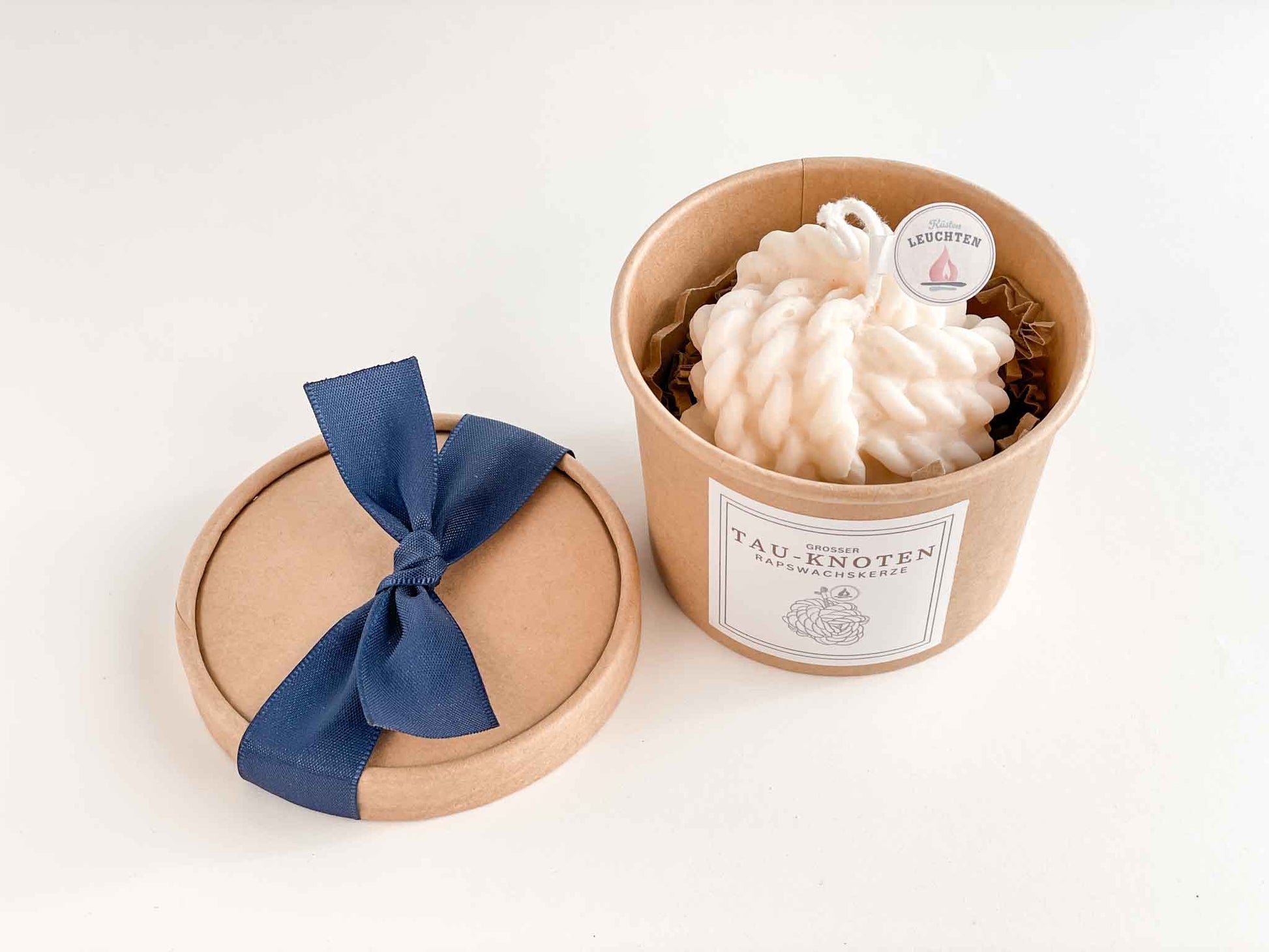 Blick von oben in die Verpackung mit großem cremeweißem Tau-Knoten als Rapswachskerze