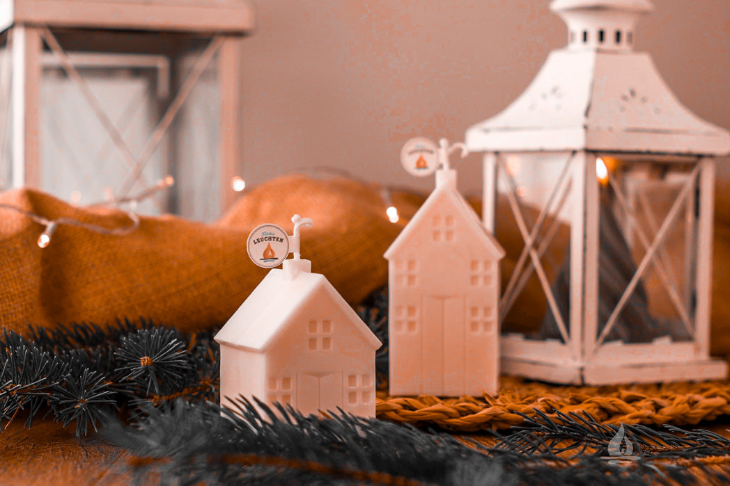 weihnachtliche Dekoration mit Kerzen in Haeuserform im Hintergrund weiße Laternen