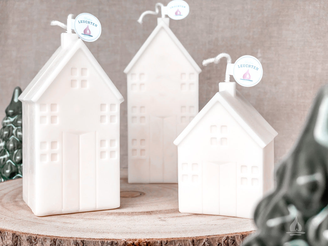 3 Haeuserkerzen auf Holzbrett