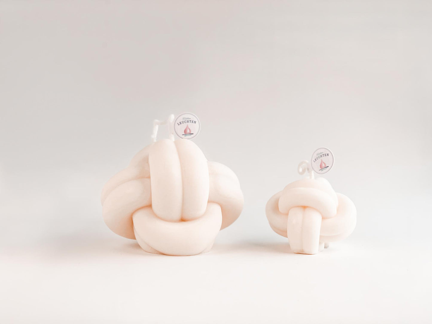 2 cremeweiße Knotenkerzen in groß und klein vor weißem Hintergrund. Für Meeresliebhaber und Seebären