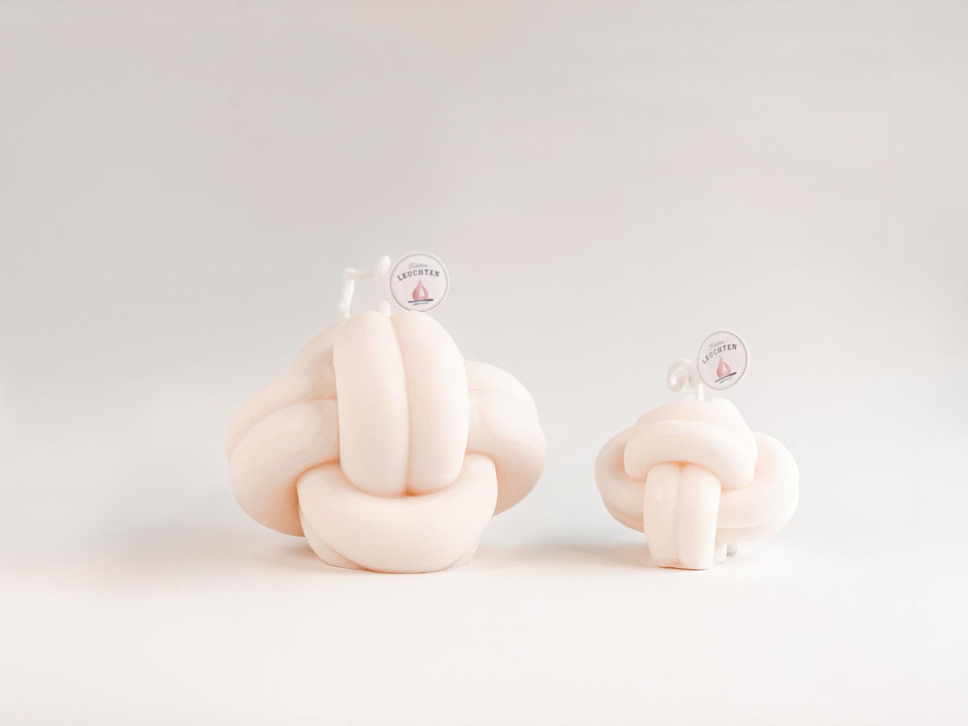 2 cremeweiße Knotenkerzen in groß und klein vor weißem Hintergrund. Für Meeresliebhaber und Seebären