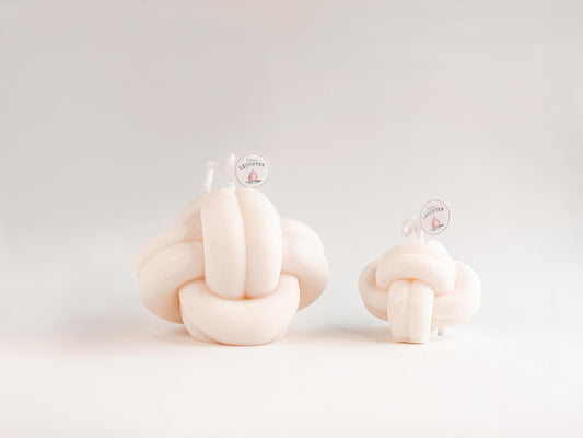 2 cremeweiße Knotenkerzen in groß und klein vor weißem Hintergrund. Für Meeresliebhaber und Seebären