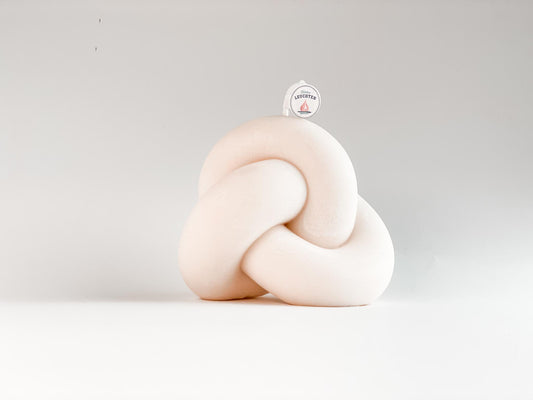 geschwungene Knotenkerze aus Rapswachs vor weißem Hintergrund