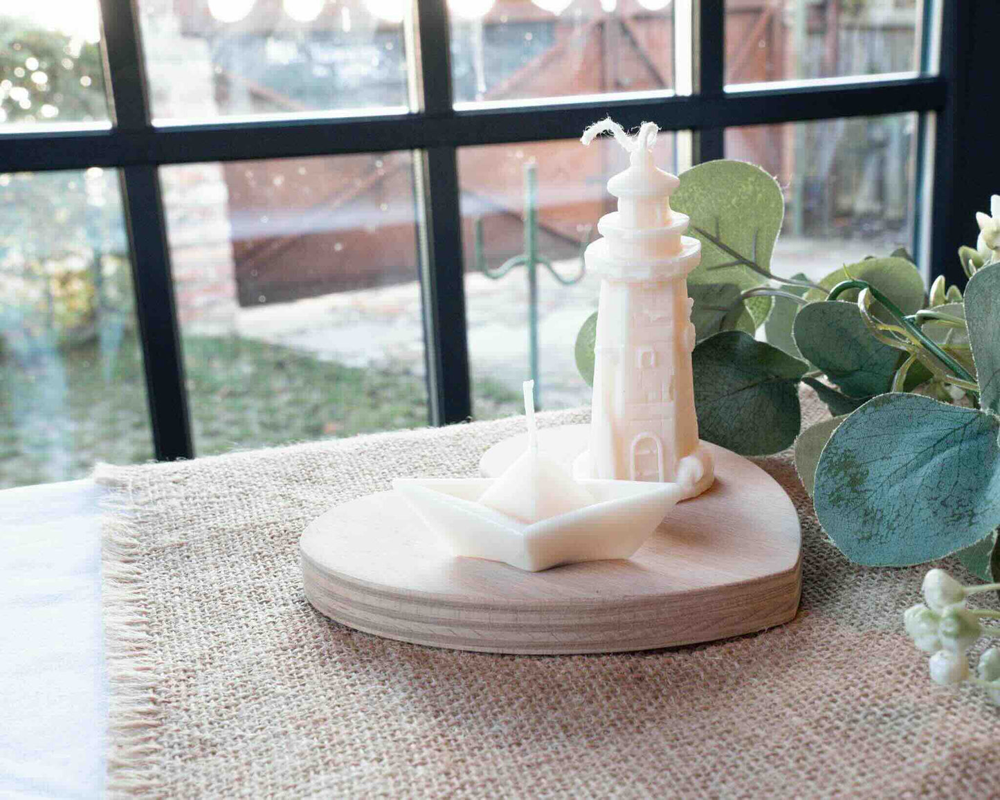 Kerzen als Leuchtturm und Schiffchen auf Jutestoff Fenster im Hintergrund