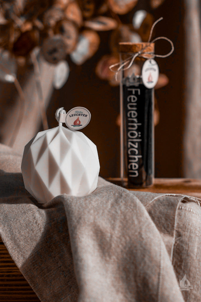 geometrische Kugel auf Tuch im Hintergrund Pflanze danebn Streichhölzer