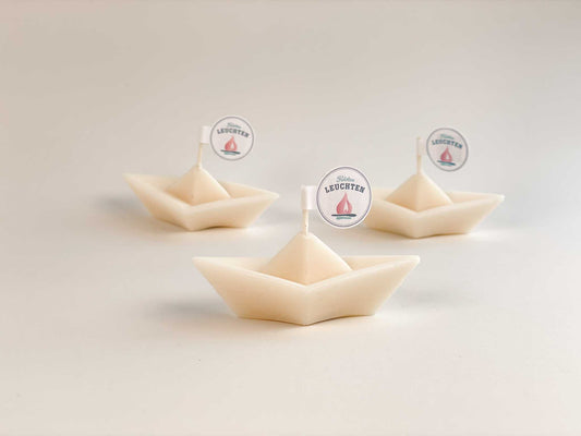 3 cremeweiße Schiffchen aus Rapswachs vor weißem Hintergrund