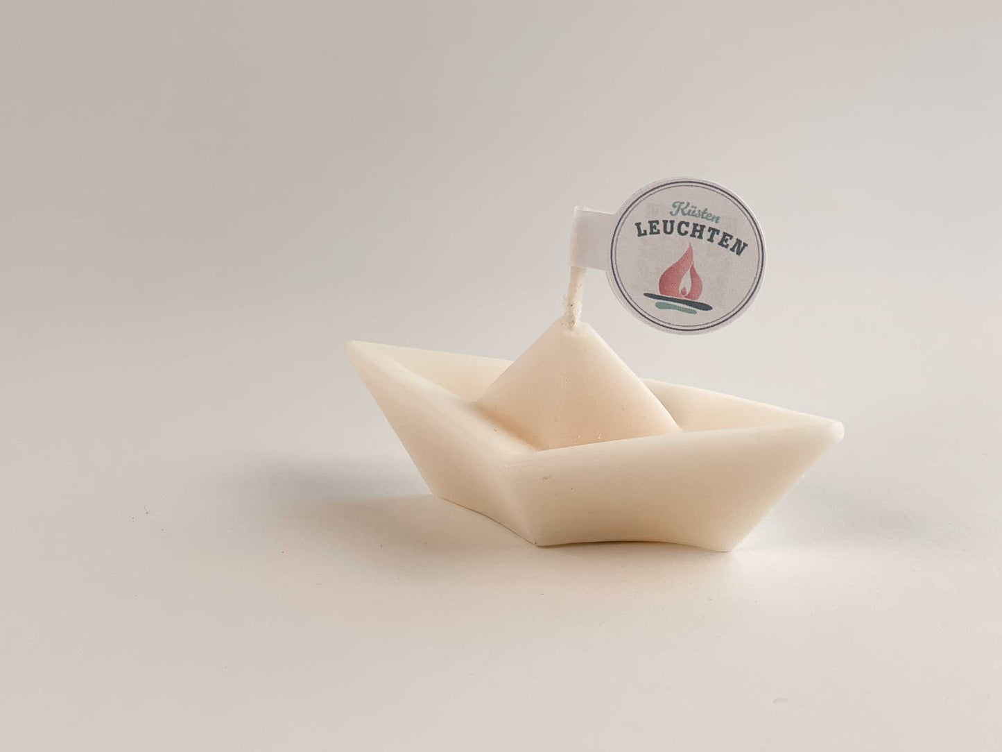 Schiffchenkerze in cremeweiß vor weißem Hintergrund