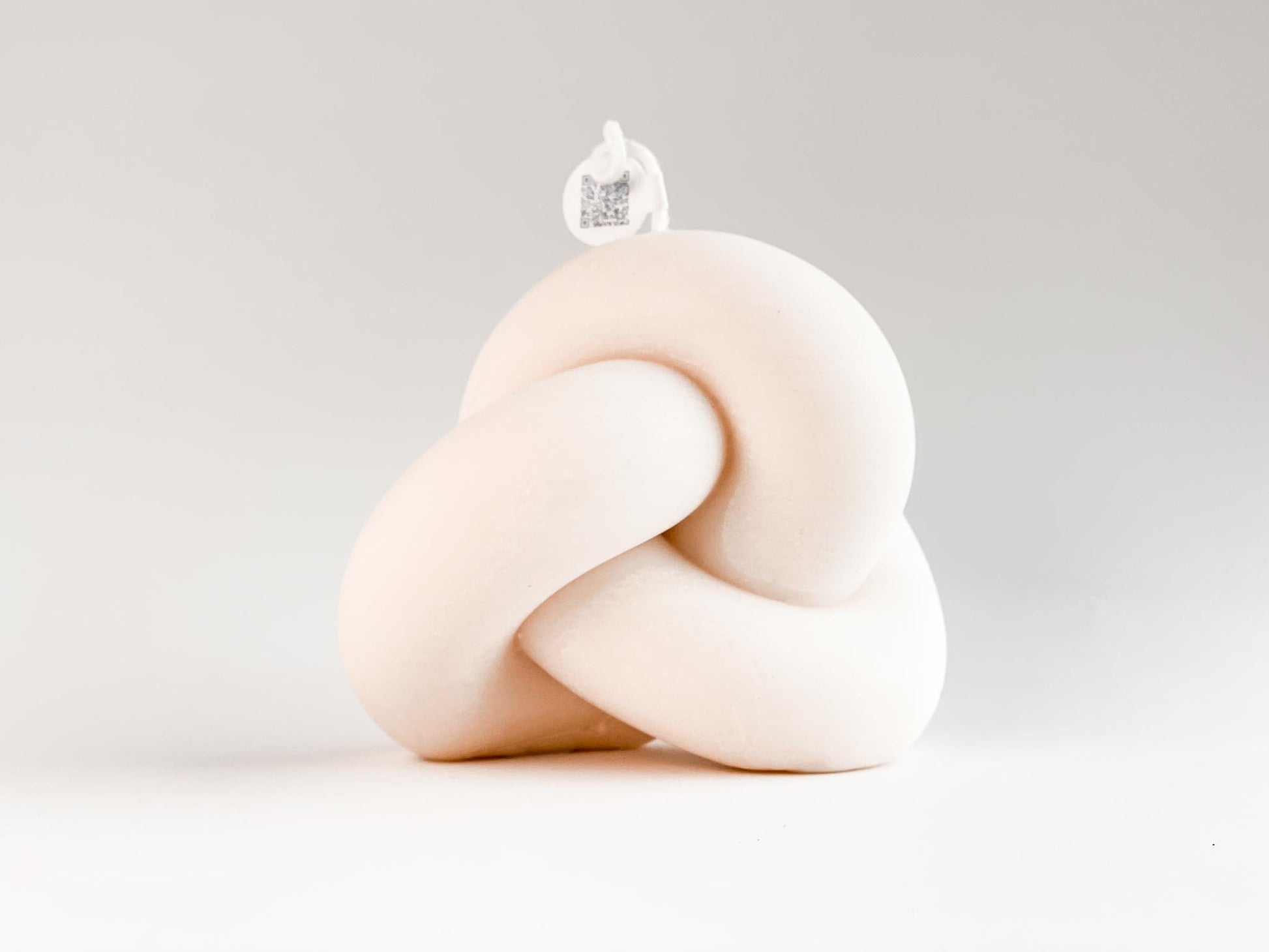 Rückseite der geschwungenen Knotenkerze aus Rapswachs vor weißem Hintergrund