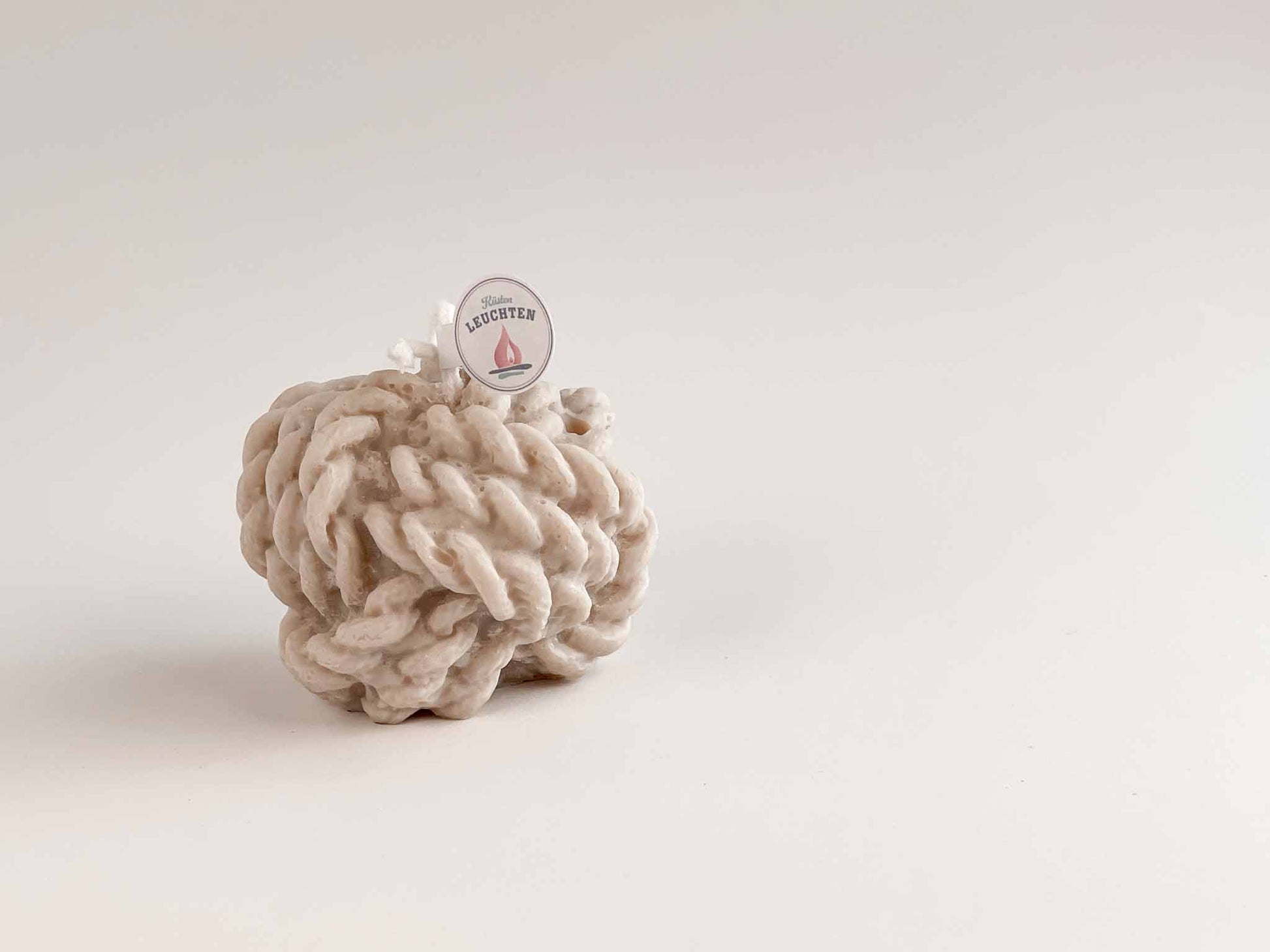 großer Tau-Knoten in grau-beige vor weißem Hintergrund