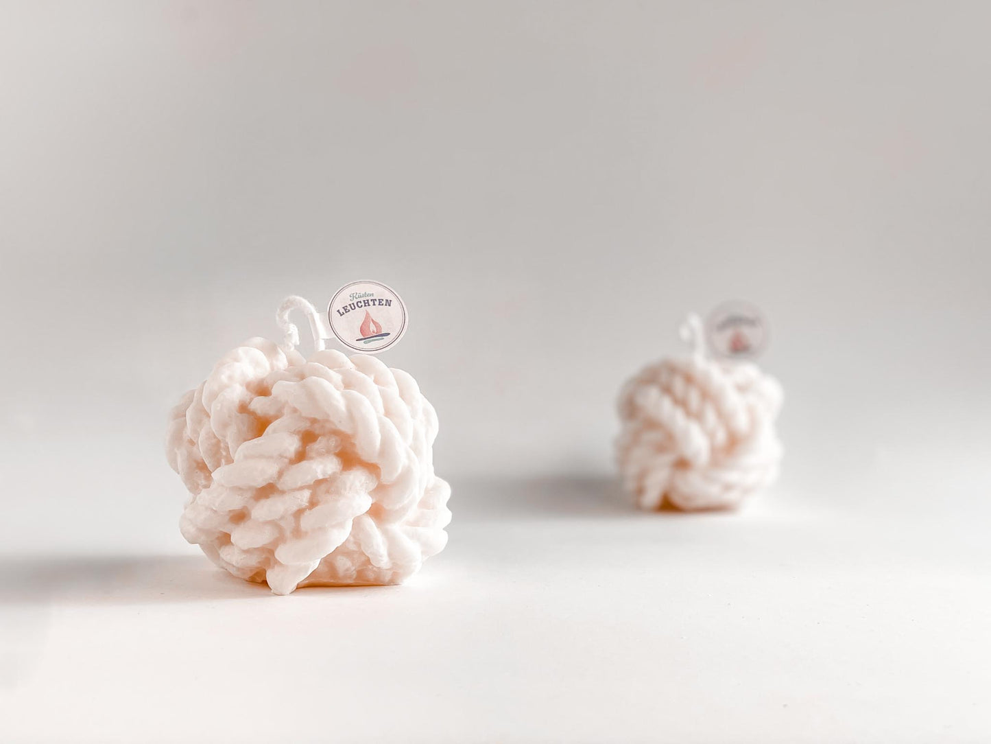 große cremeweiße Tau-Knoten Rapswachskerze vor weißem Hintergrund