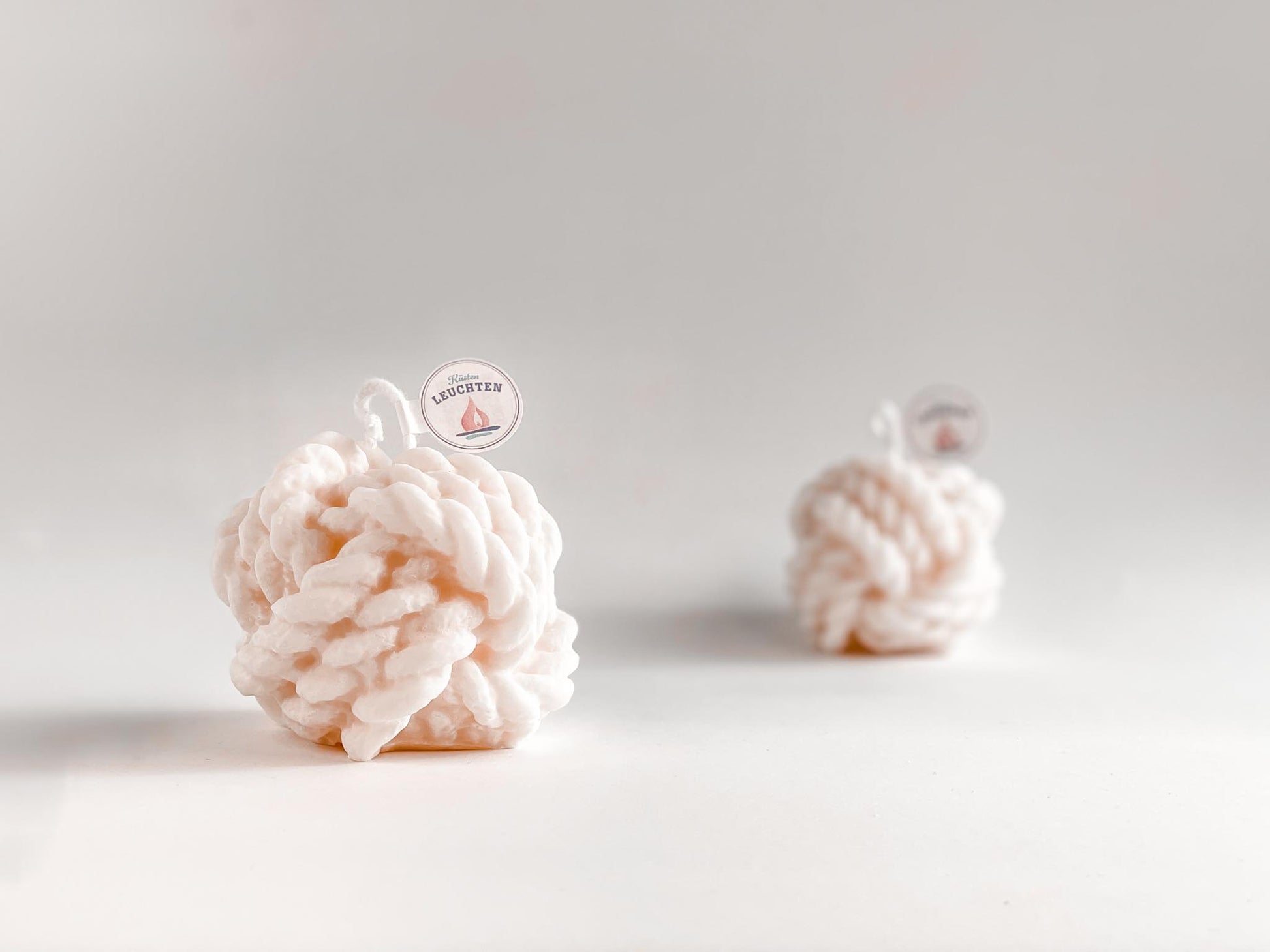 große cremeweiße Tau-Knoten Rapswachskerze vor weißem Hintergrund