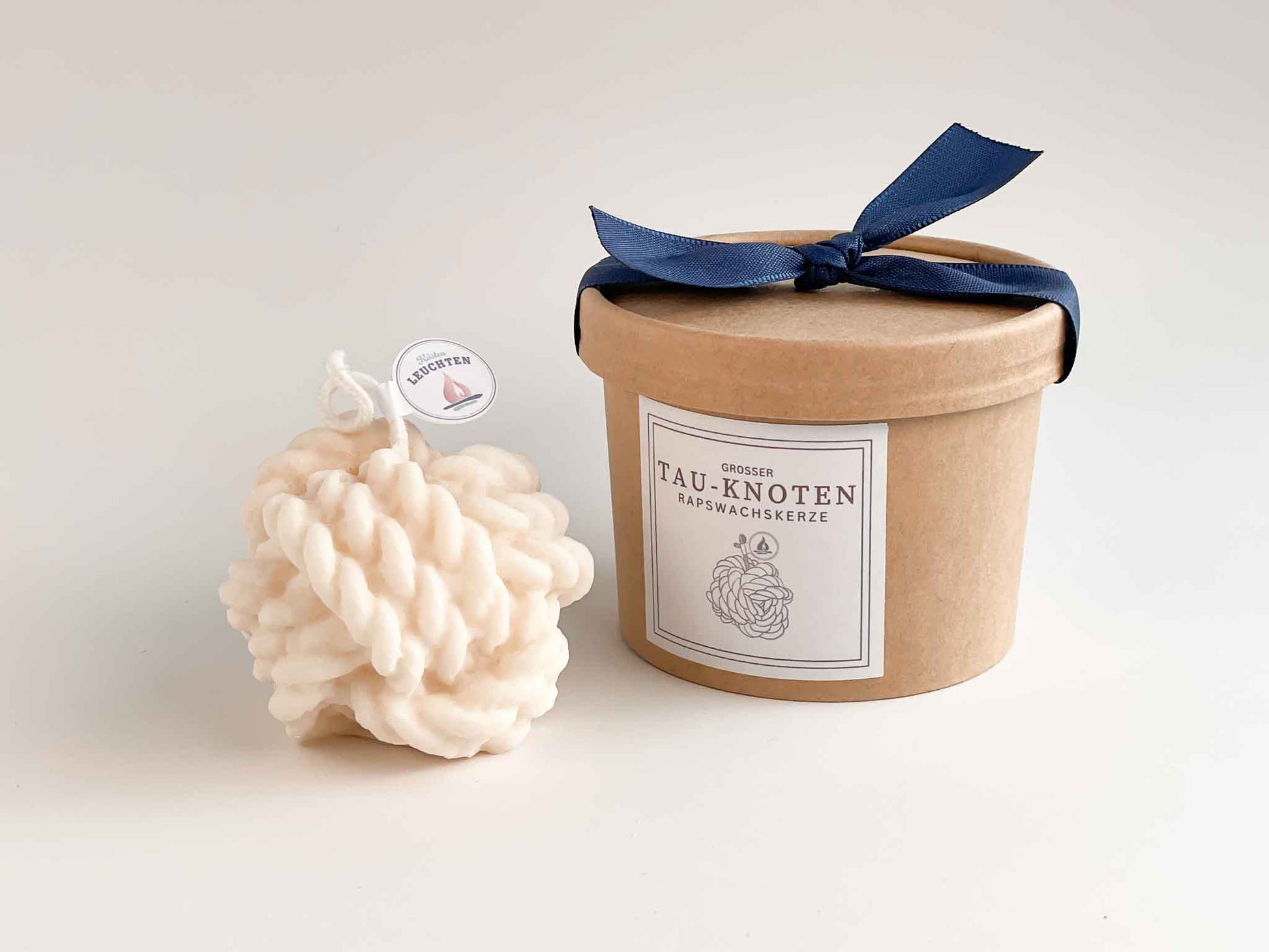Tau-Knoten daneben runde Verpackung mit blauer Schleife auf dem Deckel