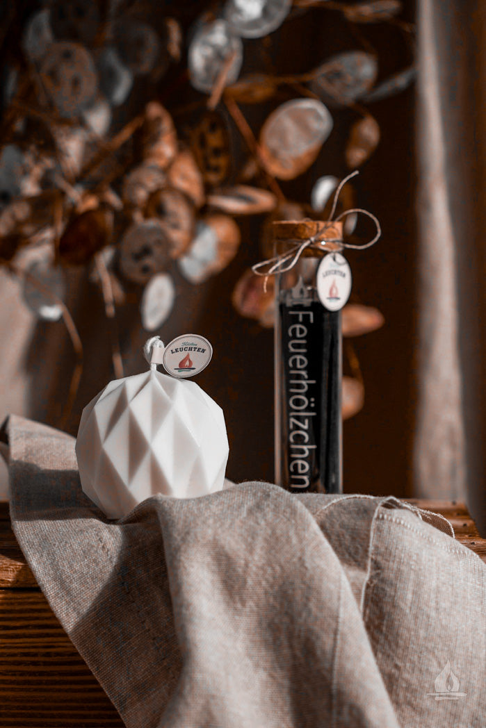 geometrische Kugelkerze auf beigem Tuch im Hintergrund Pflanze