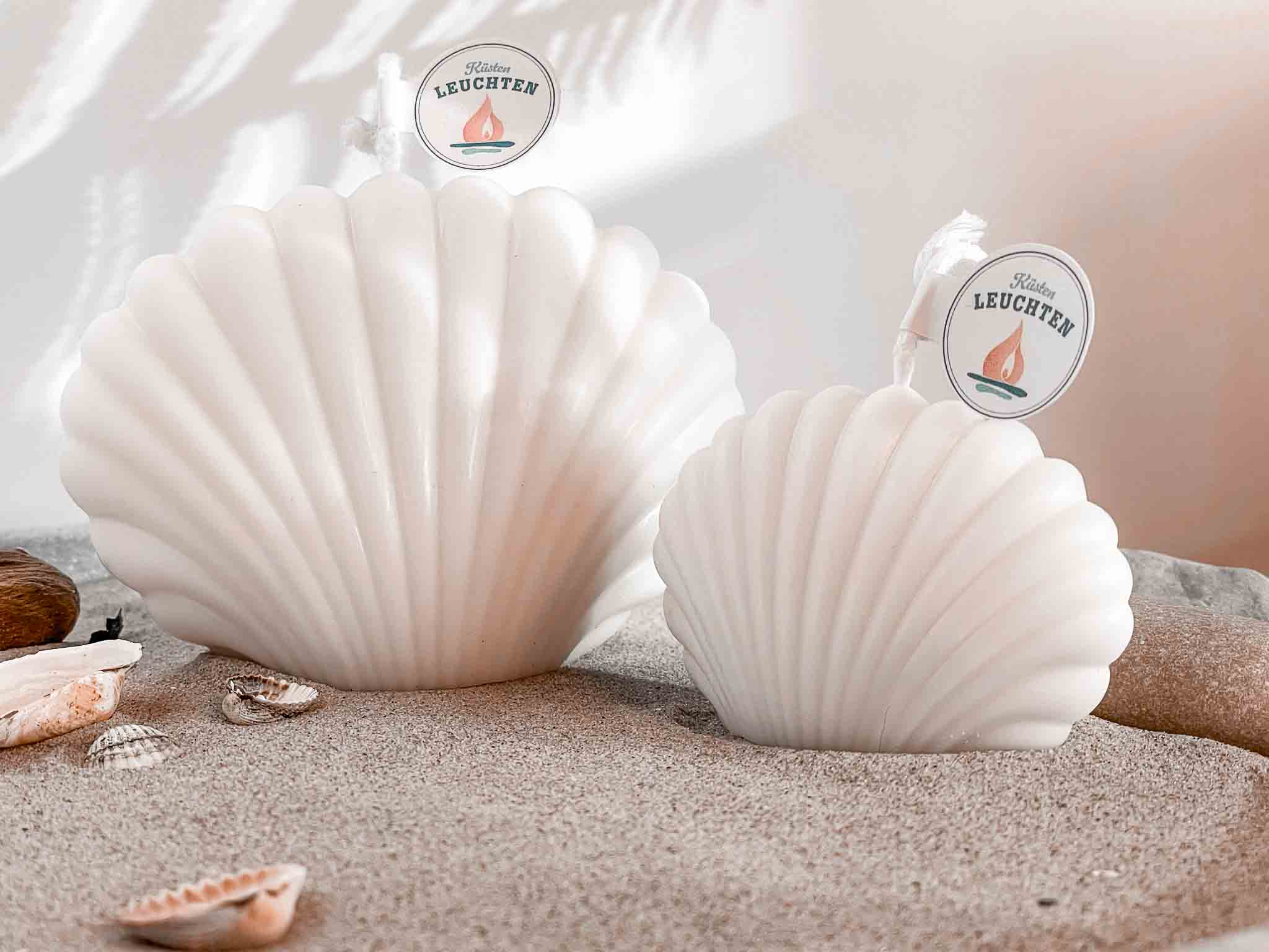 Muschelkerze groß un dklein auf Sand Muscheln im linken Vordergrund 