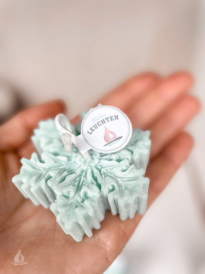 Rapswachskerze Schneeflocke in eisblau auf Handfläche