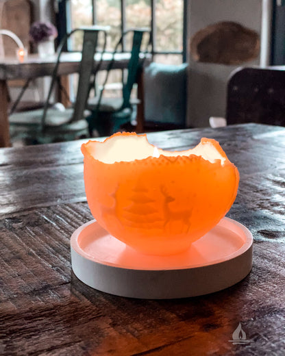 Weihnachtskugelkerze mit Rentieren brennend auf einem Holztisch im Hintergrund weitere Sitzplätze und Tische