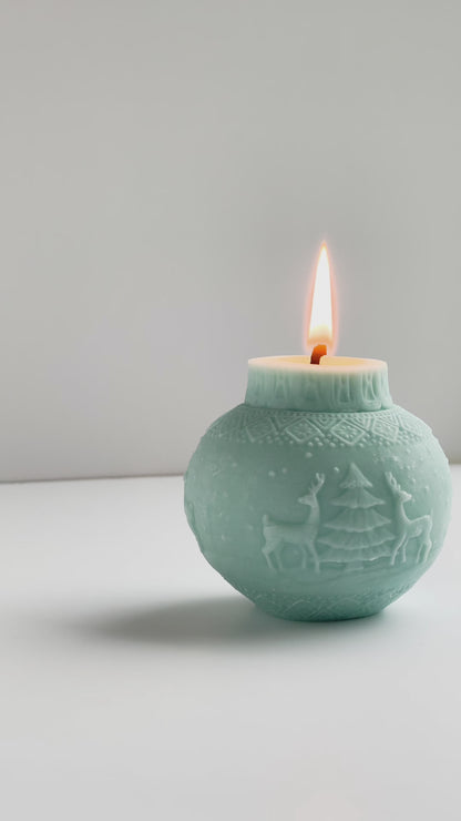 brennende Kugelkerze in eisblau mit Motiv mit zwei Rentiere und einem Tannenbaum